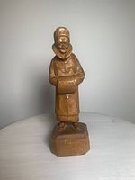Front view of wood carving showing the full figure of a man with fur muff.