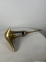 Side view of the antique brass Persian oil lamp showing the conical oil reservoir and elongated handle