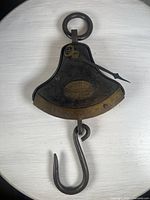 Front view of antique Salter's Quadrant Balance scale showing the dial, pointer, and bottom hook on a white table.