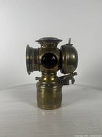 Front side view showing lamp body, large front lens, and red glass jewel on side.