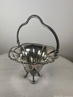Front view of silver-plated basket showing reticulated design, swing handle with leaf decoration, and footed base.