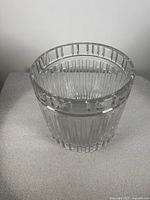 Clear barrel-shaped crystal cooler or ice bucket with vertical cuts and a rim with raised Roman numerals visible in close-up.