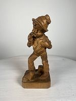 Front view of the wooden carving showing the boy with a bindle and detailed facial expression and attire.