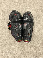 Top view of the gloves showing protective black outer shell with red accent details and adjustable velcro straps.