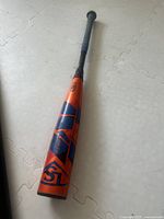 Full view of the baseball bat showing orange, red, and blue colors with Louisville Slugger branding.