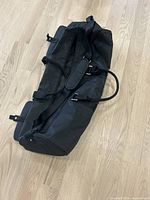 Top view of the black cylindrical gym bag showing zipper closure and shoulder strap with padding.