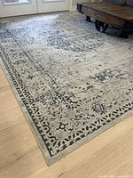 Full view of the navy and cream rug spread on a light wood floor with furniture around it, showing the distressed pattern.