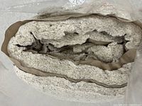 Roll of upholstery batting wrapped in plastic showing thick padded material with beige fabric backing.