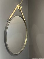 Front view of the round wall mirror showing antique black metal frame and rope hanging.
