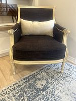 Front view of the traditional accent chair showing the cream wood frame with carved details, dark brown fabric upholstery, and beige lumbar pillow.