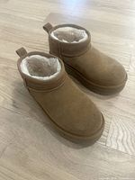 Front and side view of tan suede UGG boots showing plush faux fur lining and overall condition.