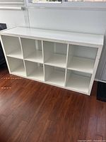 Front-side view of white cubic shelf unit with 8 compartments, showing clean lines and spacious storage compartments.