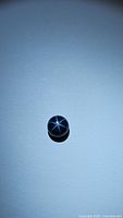 Round blue star sapphire displaying distinct 6-ray star effect on light exposure.