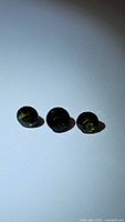 Front view showing three round green tourmalines, dark rich green color, polished surface, placed on white background.