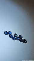 Nine natural round blue sapphire cabochon gemstones arranged on a white surface.