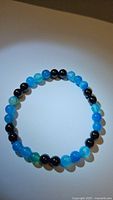 Top view of natural ocean blue agate and jet black onyx bead bracelet on a plain surface