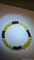 Top view of the natural lemon jade and jet black onyx bead stretch bracelet placed on a flat surface with light focused on it showing glossy yellow and matte black beads.