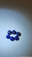 Five natural round cabochon lapis lazuli gemstones arranged on a white surface, showing their color and surface details.