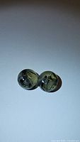 Pair of natural round moss agate cabochons, 10mm, showing inclusions and translucency under soft light on white background.