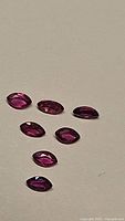 Seven marquis cut red pink natural untreated sapphires with varying clarity shown on plain background.