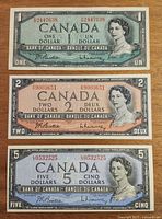 Front sides of $1, $2, and $5 1954 Canadian bank notes showing Queen Elizabeth II portrait and serial numbers.