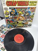 Front colorful comic-style cover of Cheap Thrills album with vinyl record and printed sheet shown.