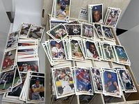 Spread of baseball cards including players in action, headshots, and posed shots from the 1990 Upper Deck series in a box.