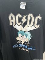Front of AC/DC black t-shirt with colorful cartoon fly and text Fly On The Wall Tour '85