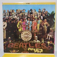 Front of the gatefold vinyl album cover showing vibrant psychedelic colors with The Beatles in colorful band uniforms and a crowded group of notable figures in the background.