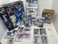 Photo showing the sealed Mats Sundin 300 piece puzzle, NHL Classic DVD collection, Upper Deck tin box with John Tavares, team calendar, model Zamboni in package, and several cards laid out.