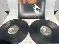 Top view of two black vinyl records with U2 center labels, positioned side by side on a white surface, showing grooves and printed text.