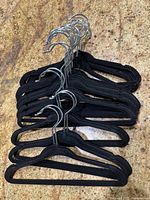 24 small black velvet kids clothing hangers stacked showing metal hooks and velvet covering