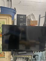 Front view of 40 inch Insignia TV with remote control on stand.