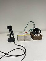 Barcode scanner with stand, receipt book packs, and paper rolls in a small basket