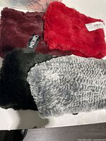 Four real rabbit fur neck warmers in various colors laid out flat, some with visible tags.