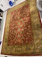 Full view of the red floral patterned carpet with a broad olive-green border