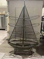 Front view of the metal sailboat shaped bottle holder showing boat hull base and metal wire racks for bottles.