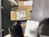 Top view photo showing opened box with clear polyethylene poly bags and stacked flat white and black shipping boxes.