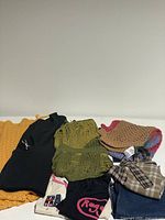 Photo of various folded knit tops and plaid clothing items showing colors and textiles.