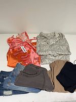 Overview of the clothing bundle showing colorful tops, various shorts in denim, caramel, and gray fabrics, and a black seamless bodysuit.