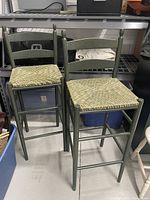 Front view of two green barstools with patterned seats showing ladder back and four legs.