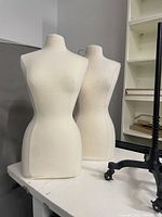 Front view of two fabric-covered dress form torsos side by side on tabletop
