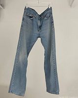 Front view of a pair of light blue Levi's jeans hanging on a hanger, showing the overall fit and color.