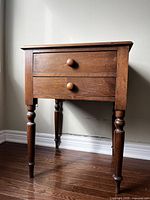 Front view of antique side table showing two drawers and turned legs