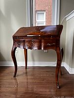 Full front view of the wooden secretary desk with slant-top closed showing overall shape and floral inlay