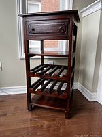 Front view of antique wooden wine rack showing the drawer with metal ring pulls and two wine bottle racks below.