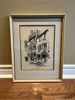 Front view of the framed painting depicting a Paris street scene with buildings, trees, and people. Painting is signed by John Haymson and titled Vieux Montmartre Paris.