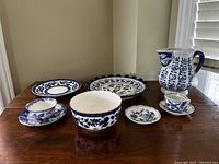 All items displayed together on table showing 2 teacups, 3 saucers, 1 bowl, 2 plates, and 1 jug in blue and white china.