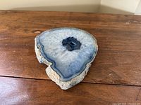 Top view of the polished blue agate stone slice showing concentric blue banding and crystalline center.