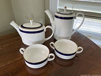 Photo showing two pitchers and two soup bowls on wooden table with window light, displaying shape and design.